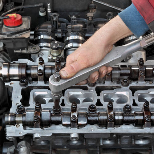 Mechanic fixing cylinder head with two camshaft of car engine with socket wrench
