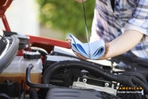 close-up of woman checking car engine oil level on dipstick